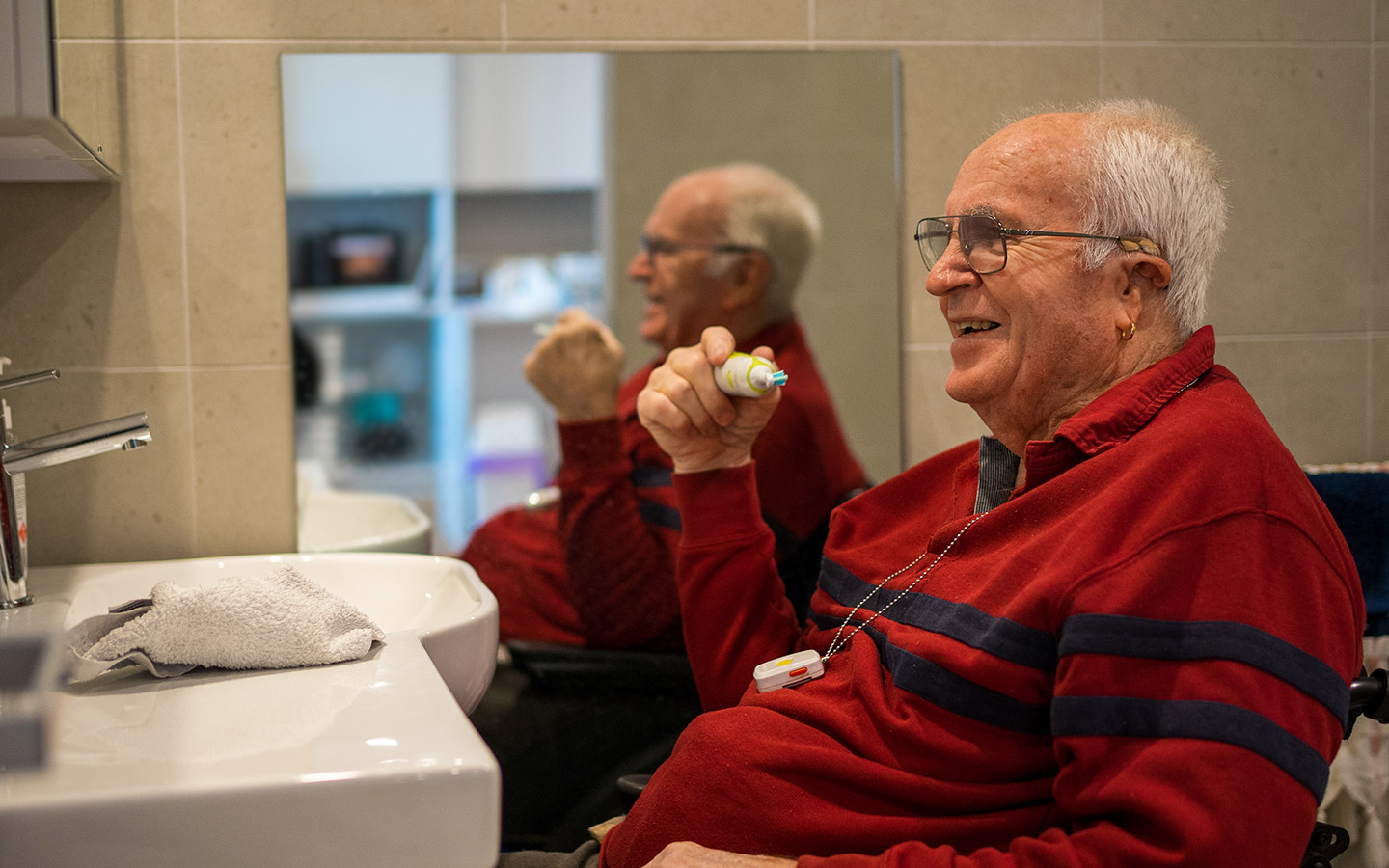 Older man in a wheelchair using a modified accessible bathroom basin