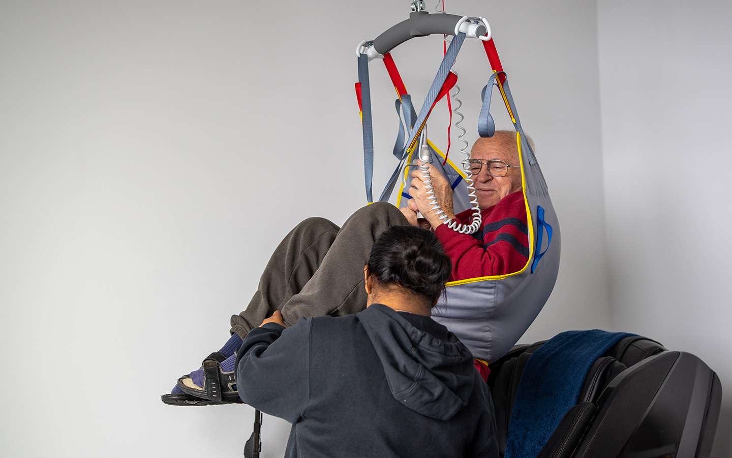 Man being transferred with a ceiling hoist and sling installed as a home modification