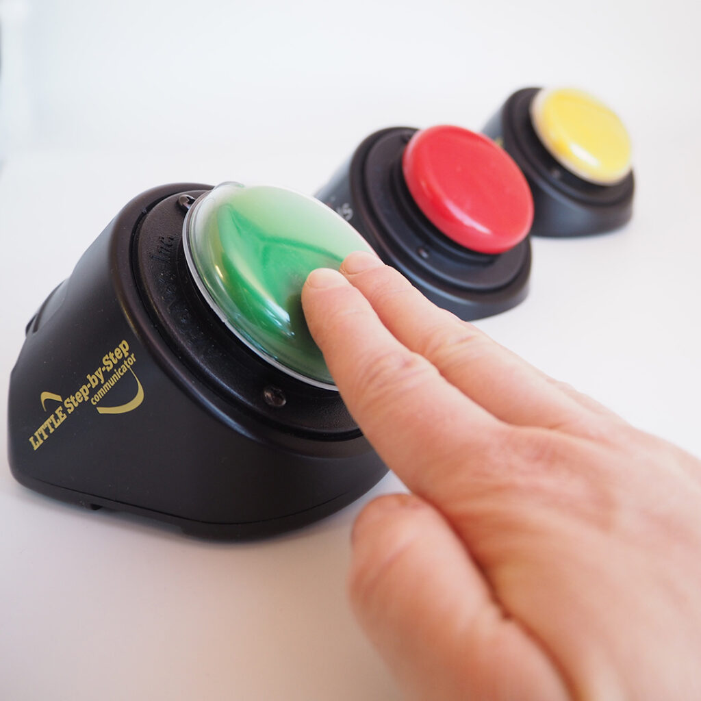A hand with two fingers pushing a green button and a red and yellow button next to them.