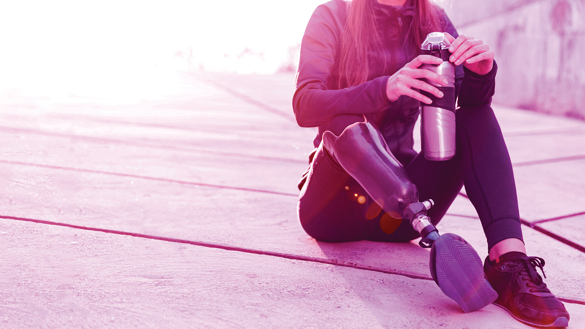 Woman with a below-knee prosthetic leg sitting outdoors after exercise
