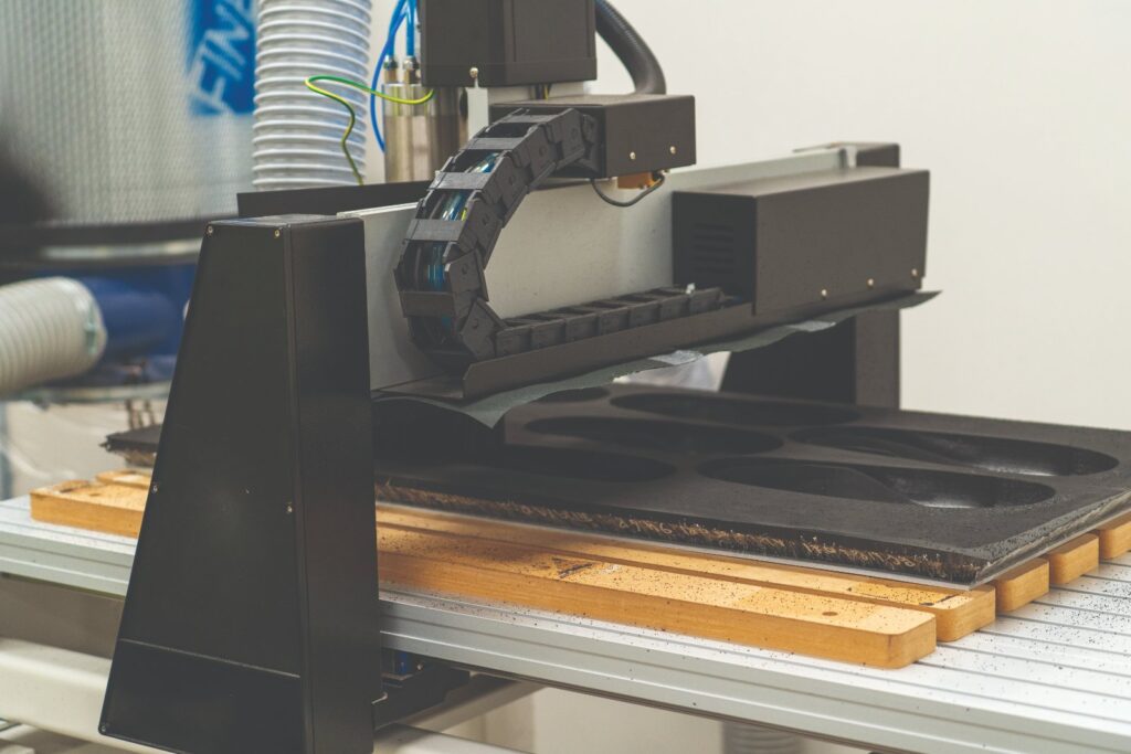 CNC machine carving custom foot orthoses from a sheet of EVA foam in the NovitaTech orthotics workshop