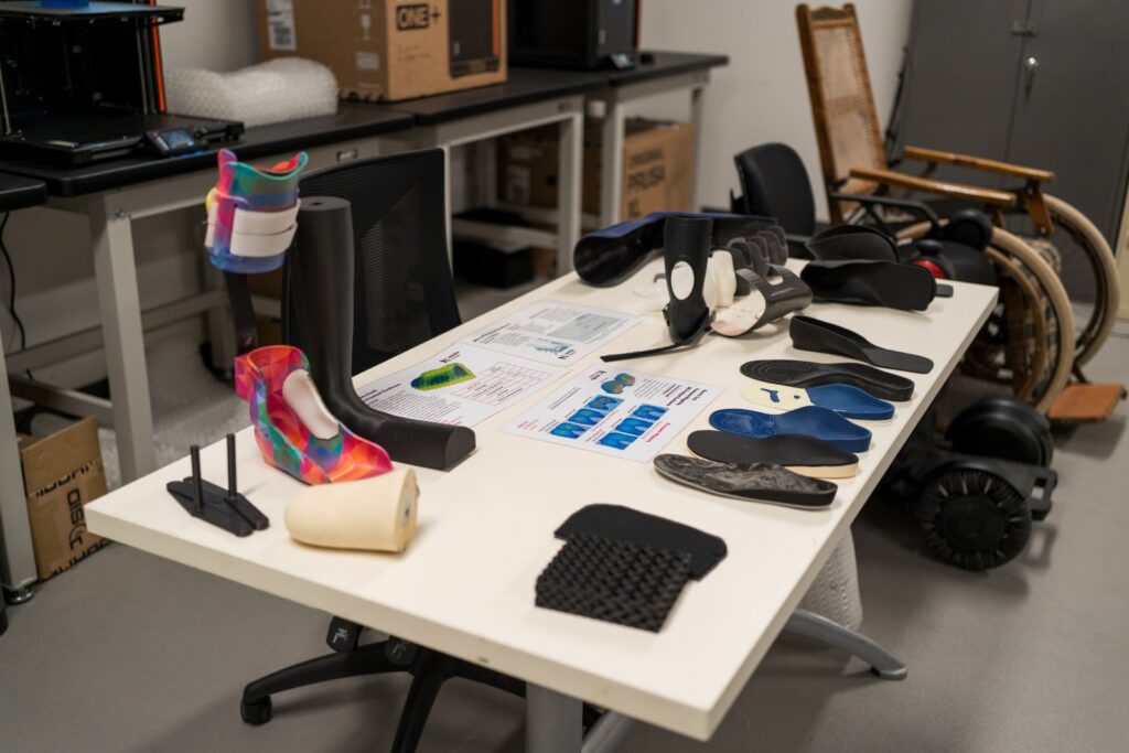 Table of NovitaTech custom devices including printed ankle-foot orthoses, carbon fibre and EVA foot orthoses, printed inners and patterned orthoses